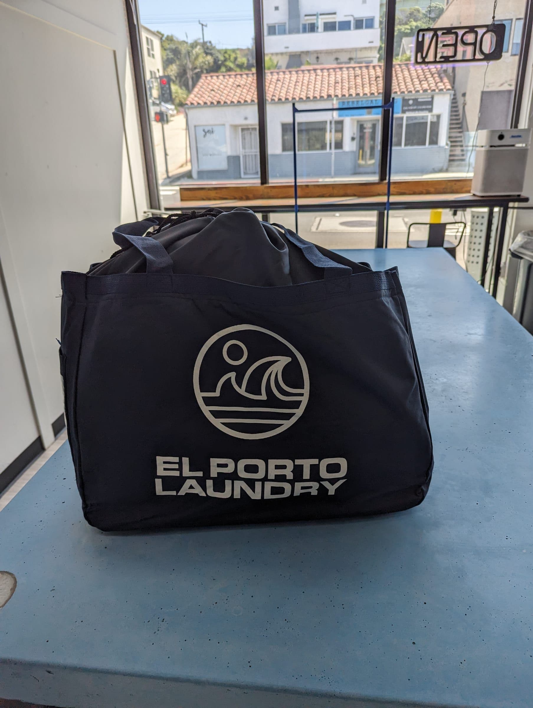 El Porto Laundry branded tote bag on the service counter at drop-off